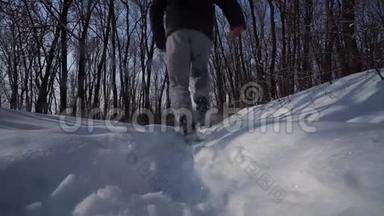 人在镜头前迈开脚步，在天空中走在雪地里，后景，鞋迹特写。 底部视图